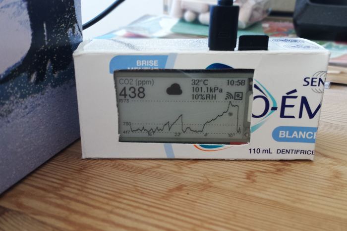 The prototype housed in half a cardboard toothpaste box, with a rectangular window cut out for the display.