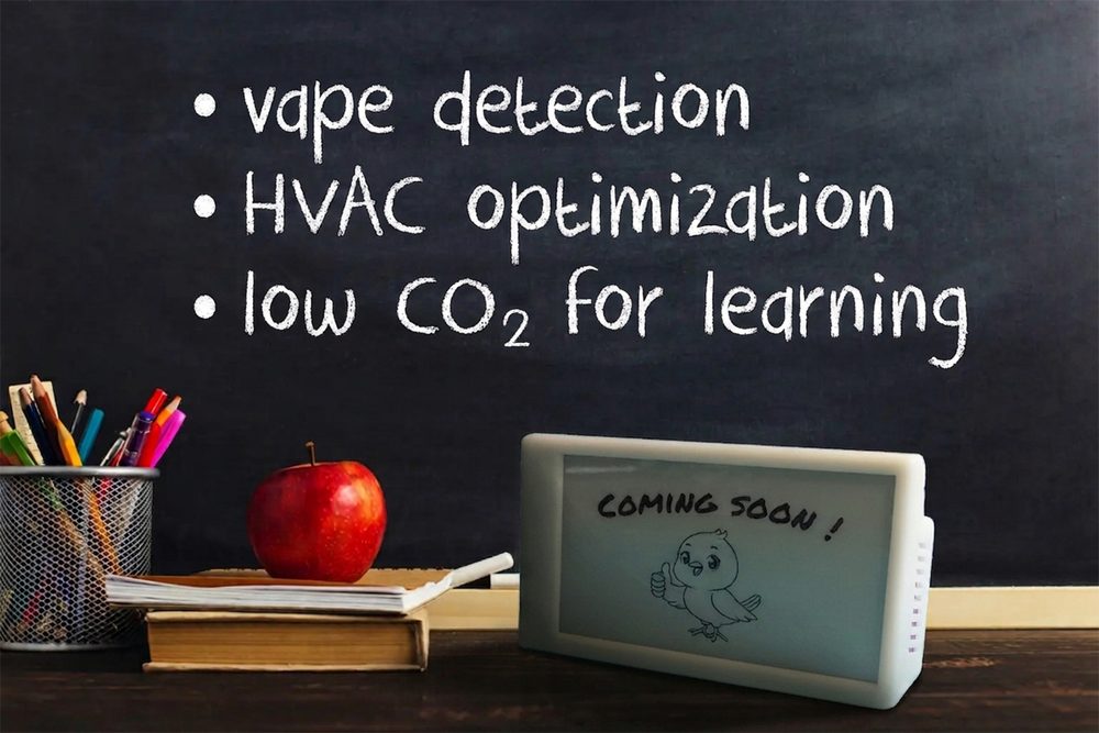 A Canary standing on a classroom desk beside an apple, a stack of books and a pot of pencils. The blackboard behind it is chalked with vape detection, HVAC optimization and low CO2 for learning, and the screen reads Coming soon.